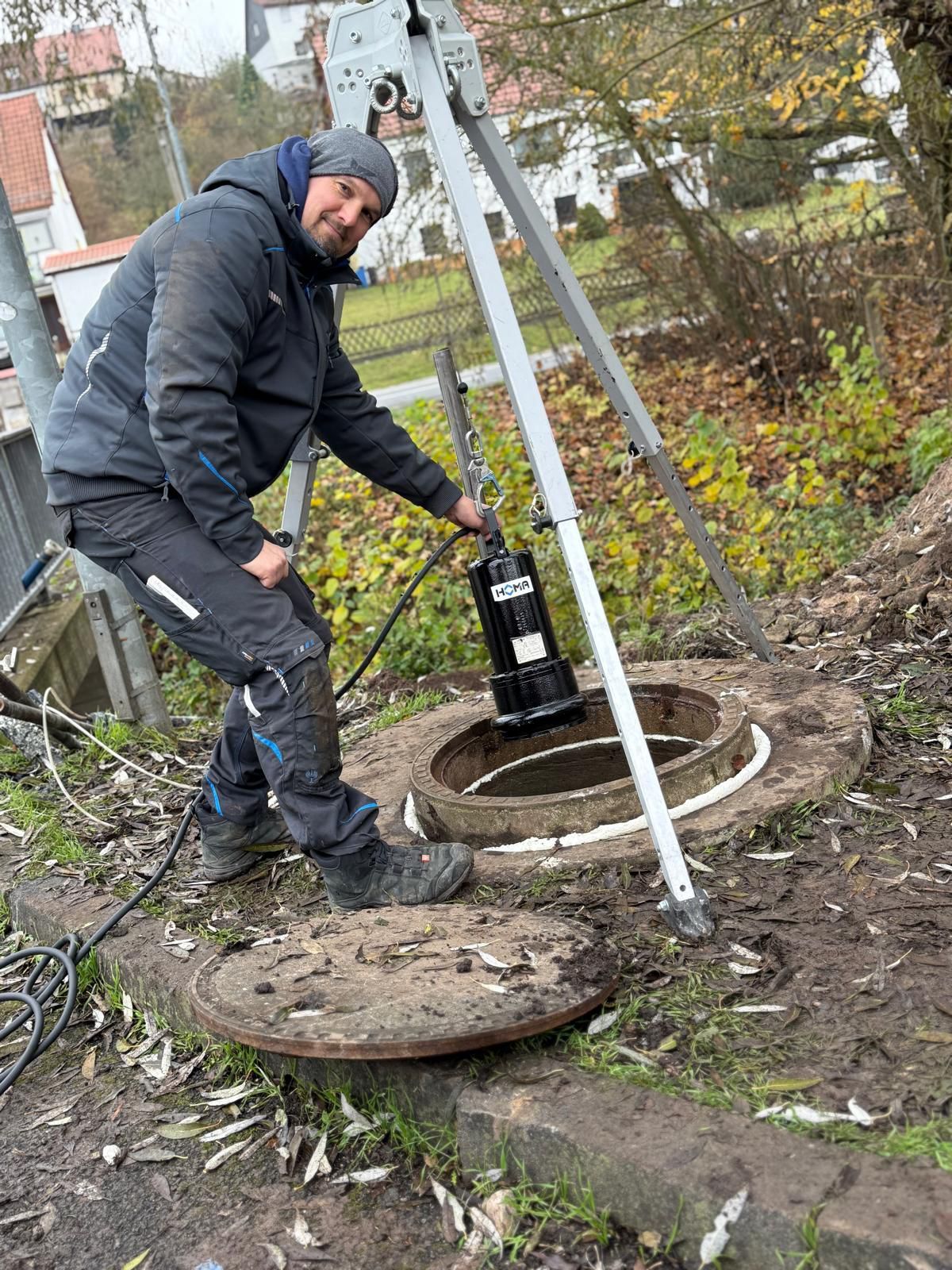 Eine Person, die eine Homa Tauchpumpe in einen Schacht herunter lässt