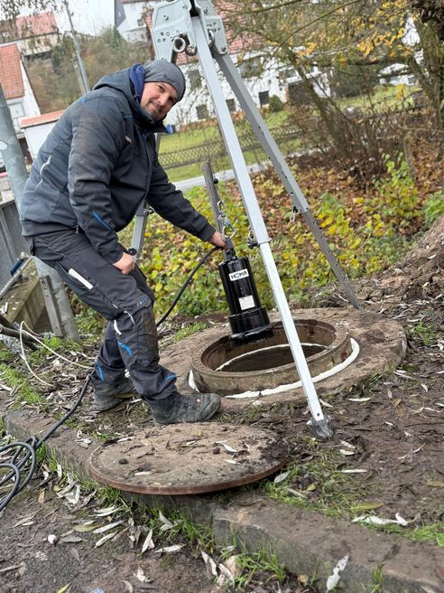 Eine Person, die eine Homa Tauchpumpe in einen Schacht herunter lässt